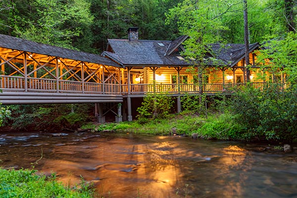 Smithgall Woods lodge cabin lit up at twilight beside a creek